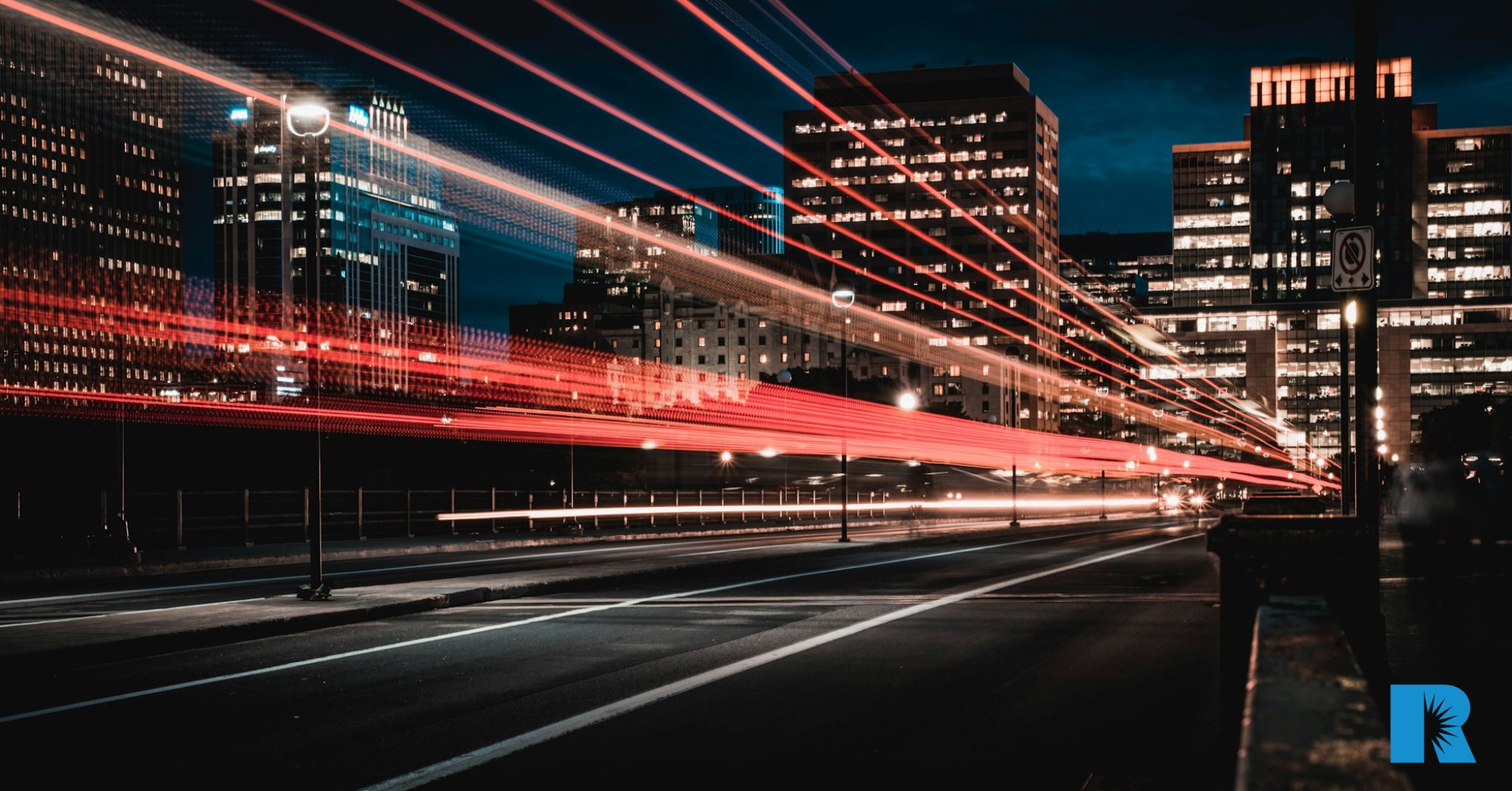 A tine-lapse photo of a street at night, illustrating speed with bands of light.