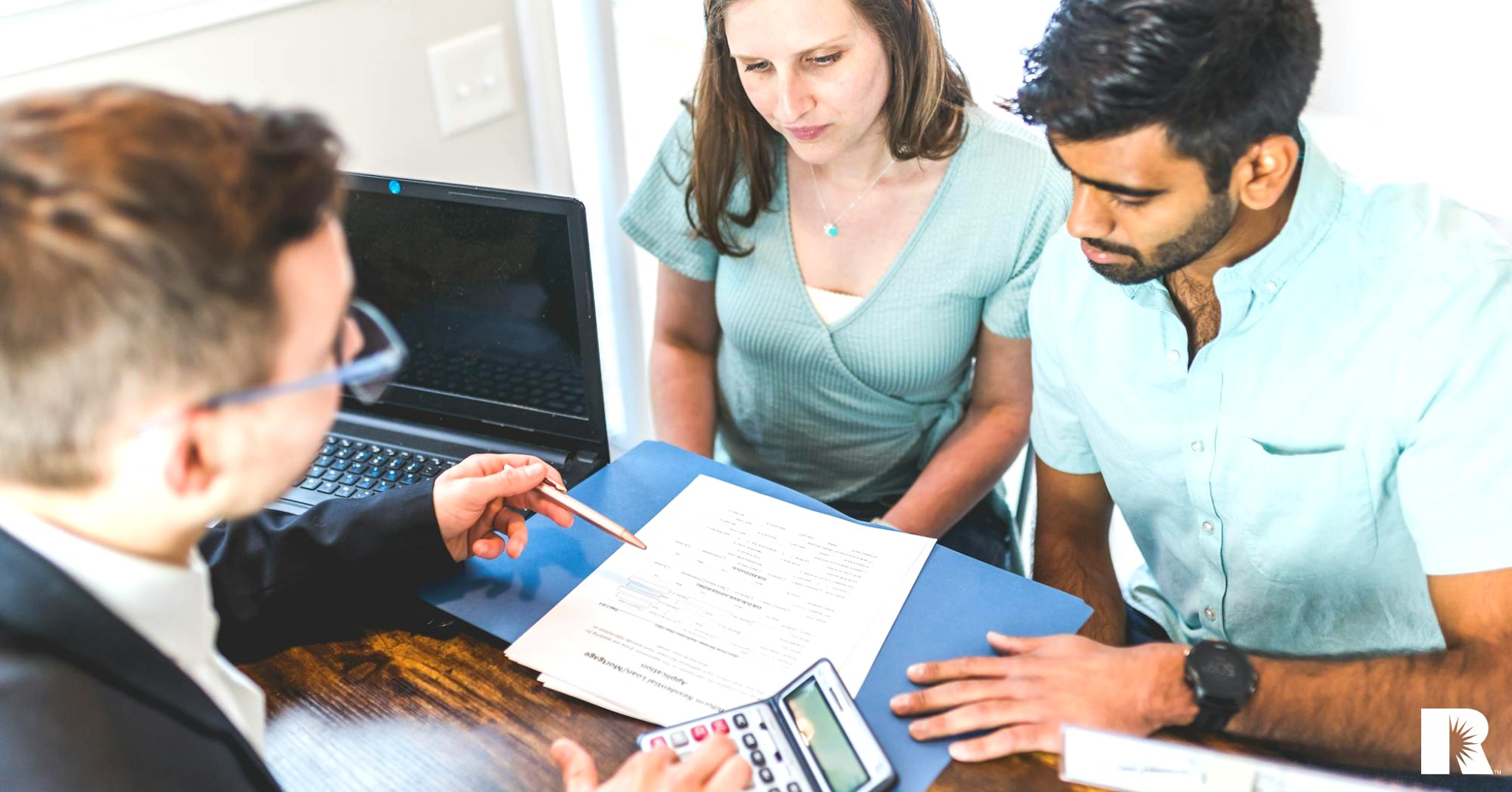 An insurance salesman reviews a policy with two customers.