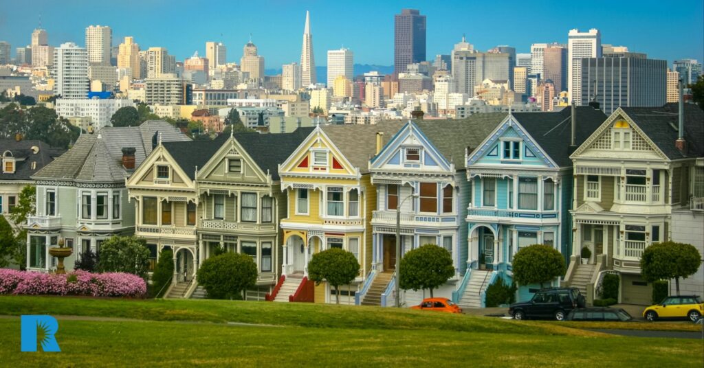 Photo of a series of row homes, with cars parked outside.
