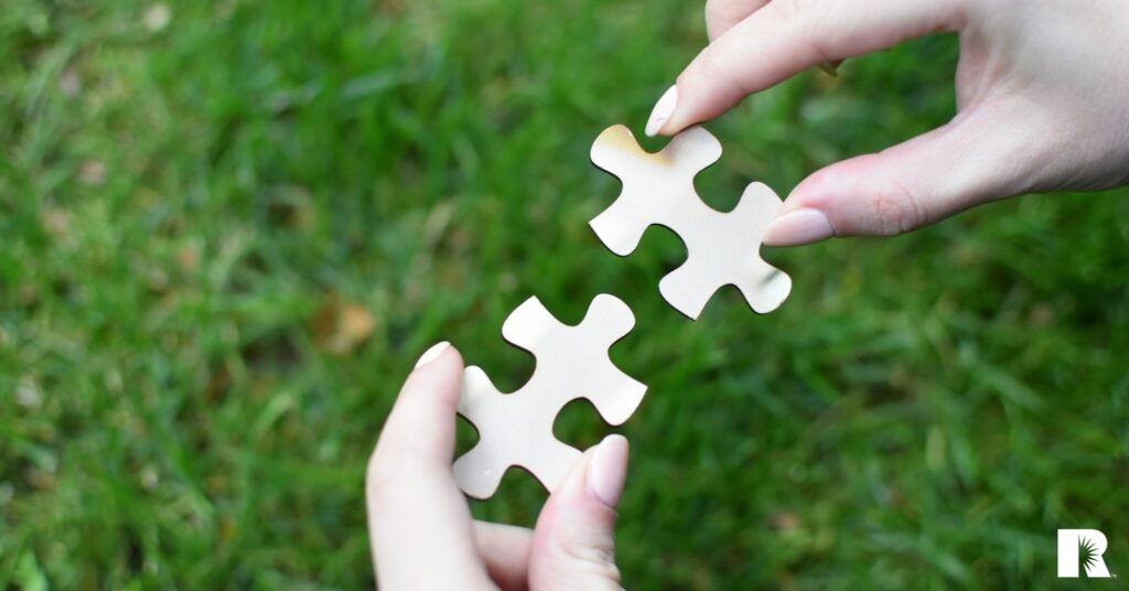 Hands holding two puzzle pieces, symbolizing a relationship.